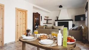 A dining area with a wooden table set for breakfast, including croissants, juice, and a bottle of Queso. - Campi a Villa Alicia (Porcuna)