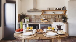 A modern kitchen with a built-in oven, a refrigerator, and a wooden dining table set for breakfast. - Campi a Villa Alicia (Porcuna)