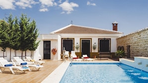A poolside area with lounge chairs, a small pool, and a building with a tiled roof. - Campi a Villa Alicia (Porcuna)