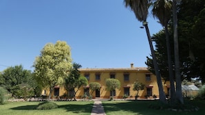 A yellow building with a stone pathway leading to the entrance. - Casa Rural del Jardin (Priego de Córdoba)