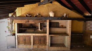A rustic kitchen with wooden cabinets, a brick oven, and a stone countertop. - Casa Rural del Jardin (Priego de Córdoba)
