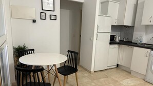 A compact kitchen with white cabinets, a white countertop, and a round table with four chairs. - Apartamento en el Centro Hist Rico (Málaga)