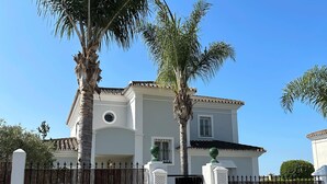 A two-story house with a white facade, a black gate, and a palm tree in the foreground. - Villa Maisa Luxury Marbella (Marbella)