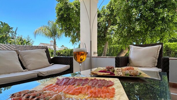 A table with seafood, a glass of beer, and a view of greenery. - Villa Maisa Luxury Marbella (Marbella)
