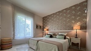 A bedroom with two beds, a window with curtains, a patterned wall, and bedside lamps. - Villa Maisa Luxury Marbella (Marbella)