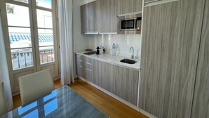 Eine moderne Küche mit eingebauter Mikrowelle, einem Spülbecken und einem Fenster mit Blick auf einen Balkon.