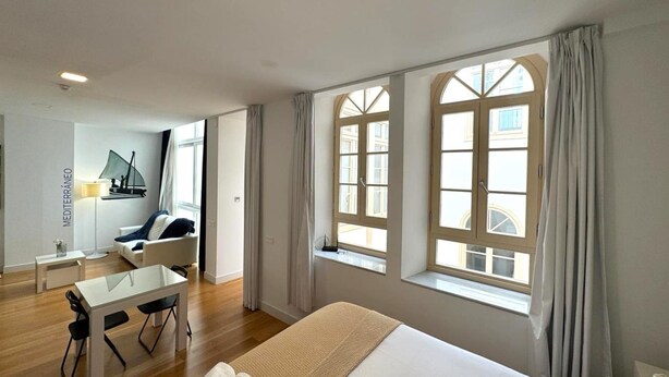 Una habitación de hotel con una cama grande, un escritorio y dos ventanas con cortinas.