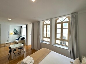 A hotel room with a large bed, a desk, and two windows with curtains. - Premium and Cathedral View 1 (Málaga)
