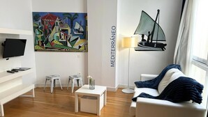 Una sala de estar moderna con un televisor de pantalla plana, un cuadro, una lámpara y un sofá.