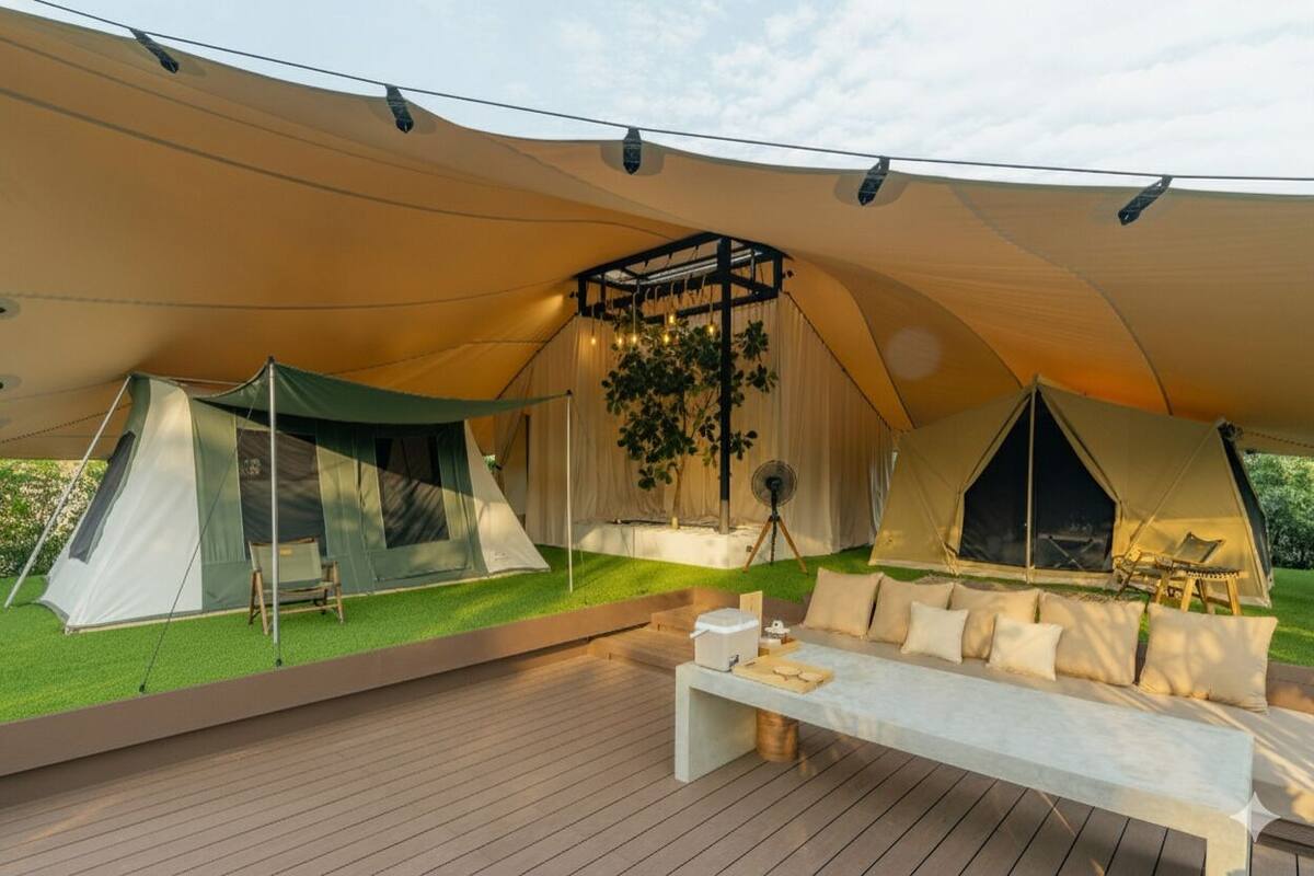 A tented accommodation with a covered deck, a seating area, and a small table.
