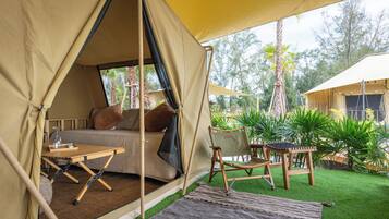 A tented accommodation with a bed, a table, and a chair.