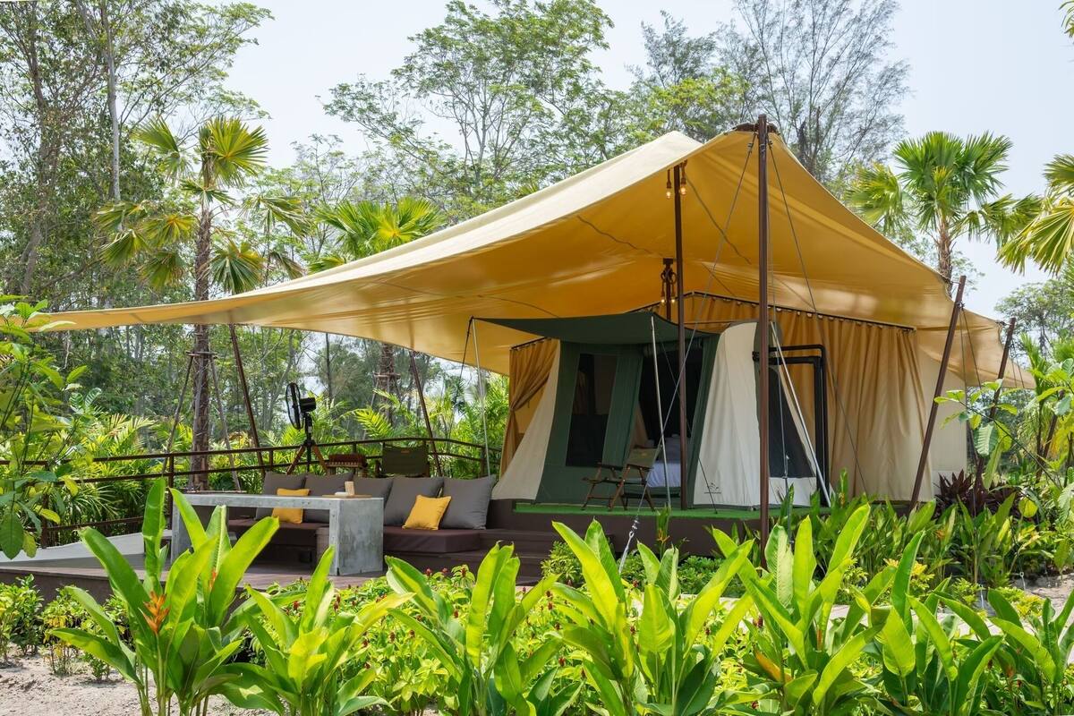 A tented accommodation with a covered seating area, surrounded by lush greenery.