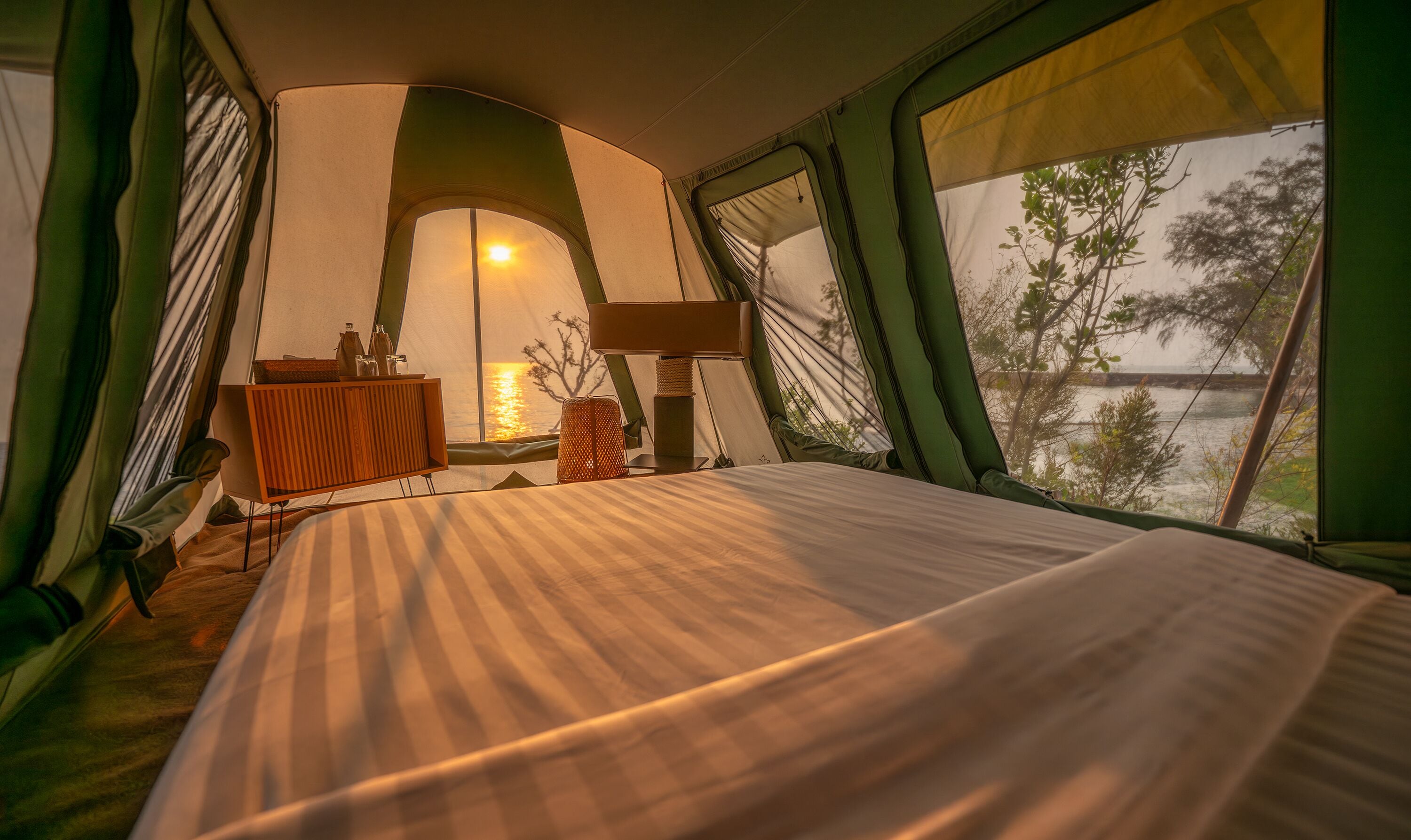 A tented room with a bed, a table, and a lamp.