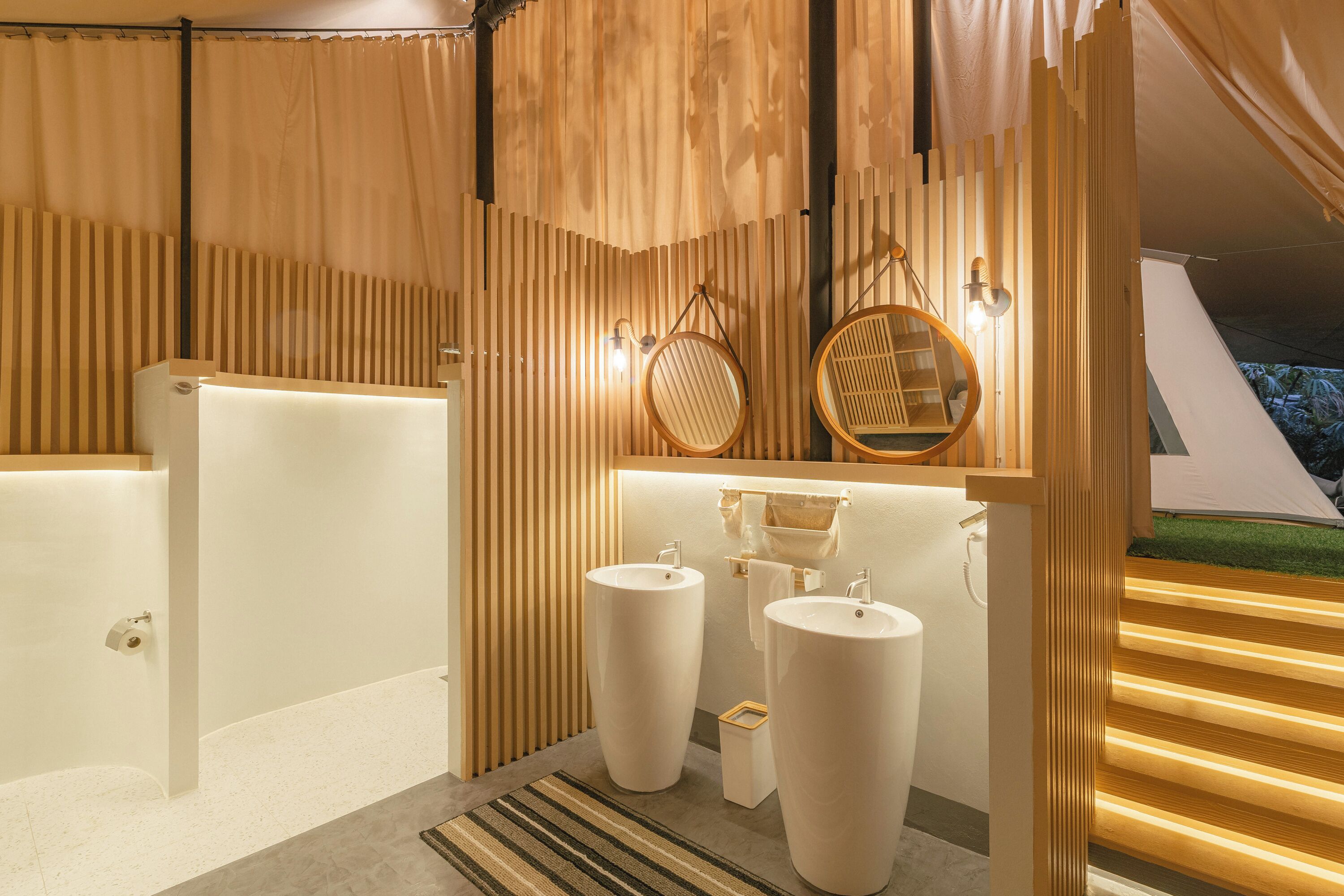 A modern bathroom with a large bathtub, two sinks, and a wooden slatted wall design.