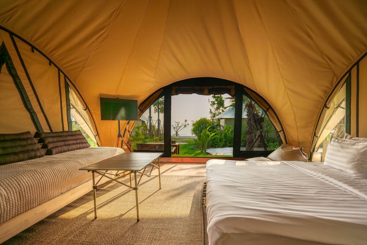A tented accommodation with two beds, a table, and a TV.