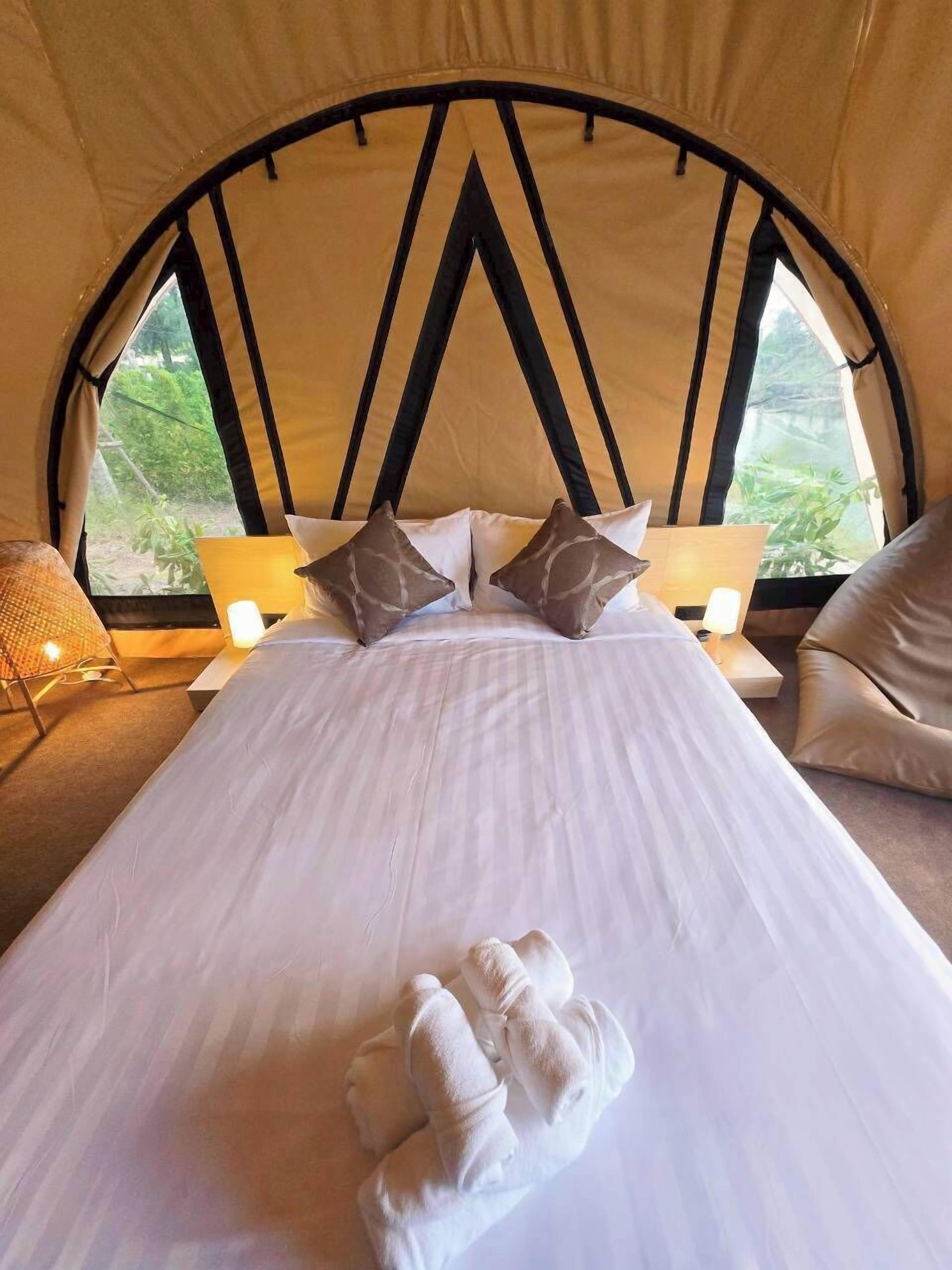 Una habitación tipo tienda de campaña con una cama, almohadas y una toalla.