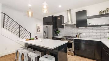 A modern kitchen with a central island, stainless steel appliances, and black cabinetry.