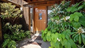 Une maison en bois avec une porte en bois et un petit porche.