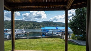 Un espace extérieur abrité offrant une vue sur un lac, des bateaux et une colline boisée.