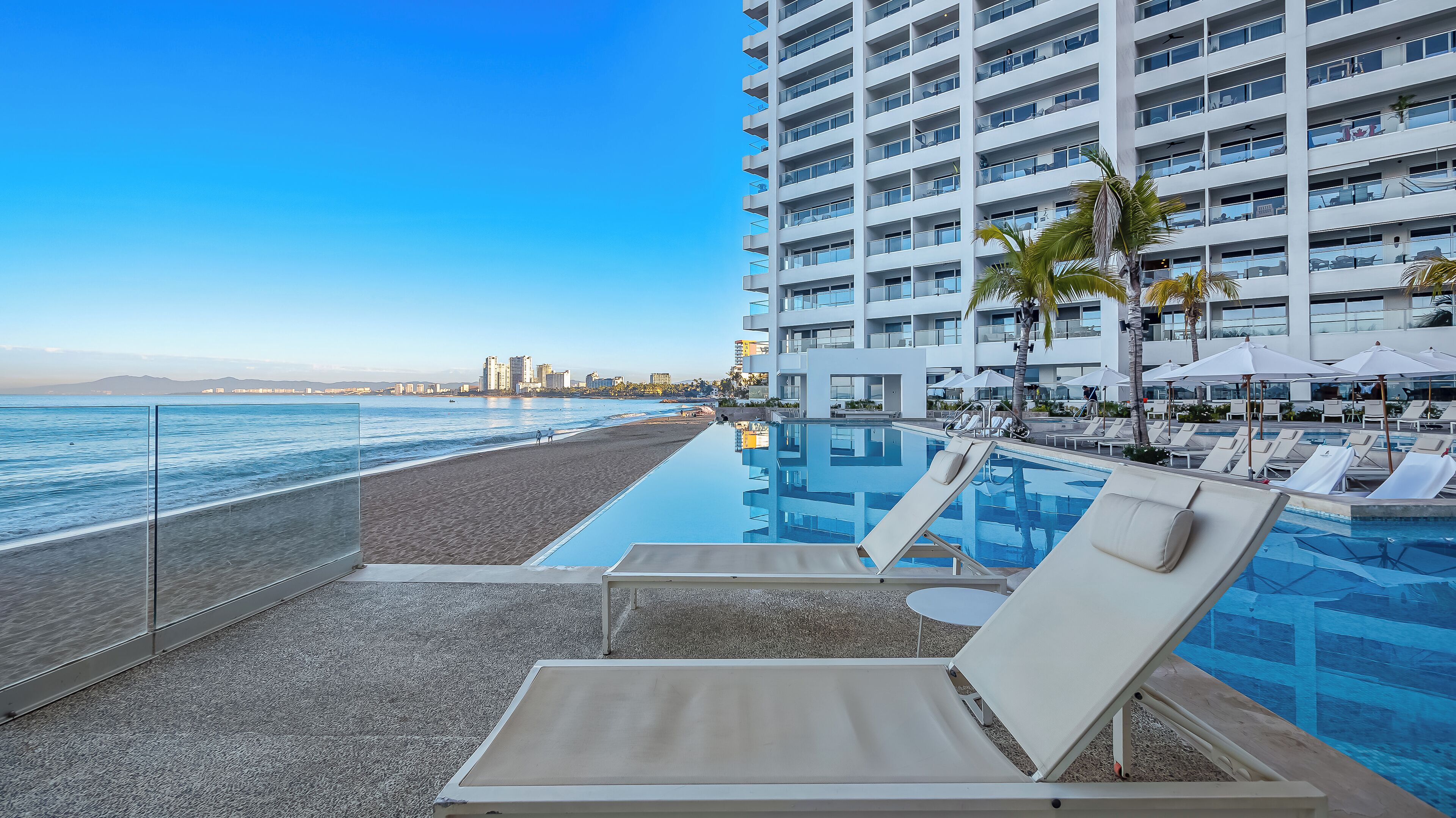 Una piscina dell'hotel con lettini prendisole e vista sulla spiaggia e sull'oceano.