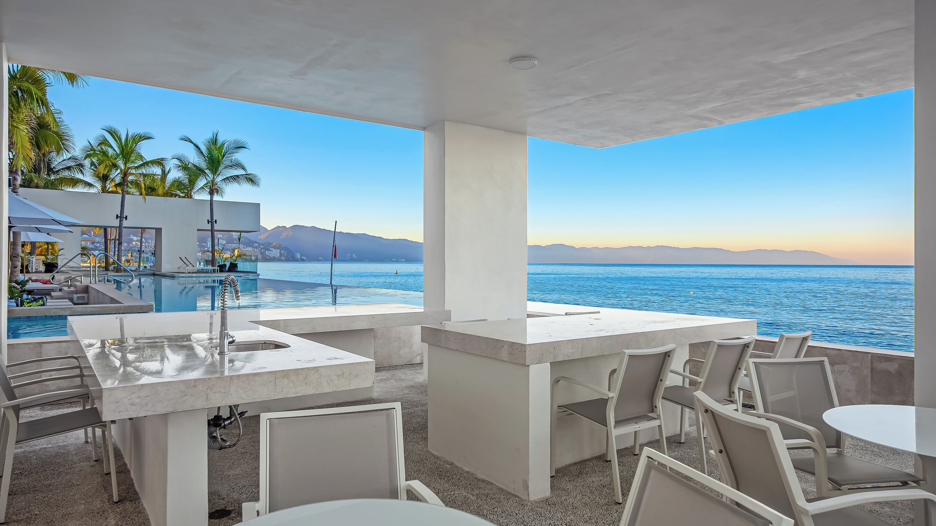 Un espace extérieur moderne, aménagé avec des sièges, une piscine et une vue sur la mer.
