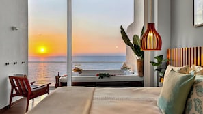 A bedroom with a large window overlooking the sea, a bed with a view, a hanging light fixture, and a plant. - Panoramic Oceanview 4BR Penthouse with Private Hot Tub (Puerto Vallarta)