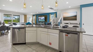 A modern kitchen with granite countertops, stainless steel appliances, and a large island. - The Enchanted Collection: Burma Manor (Kissimmee)