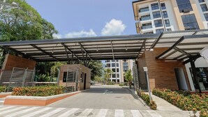 Ingresso di un edificio moderno con una tettoia, un'area di parcheggio e cielo sereno.