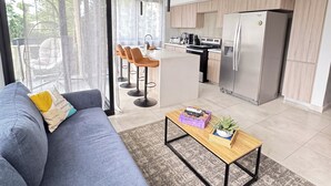 Un soggiorno moderno con un divano, un tavolino e vista sulla cucina.