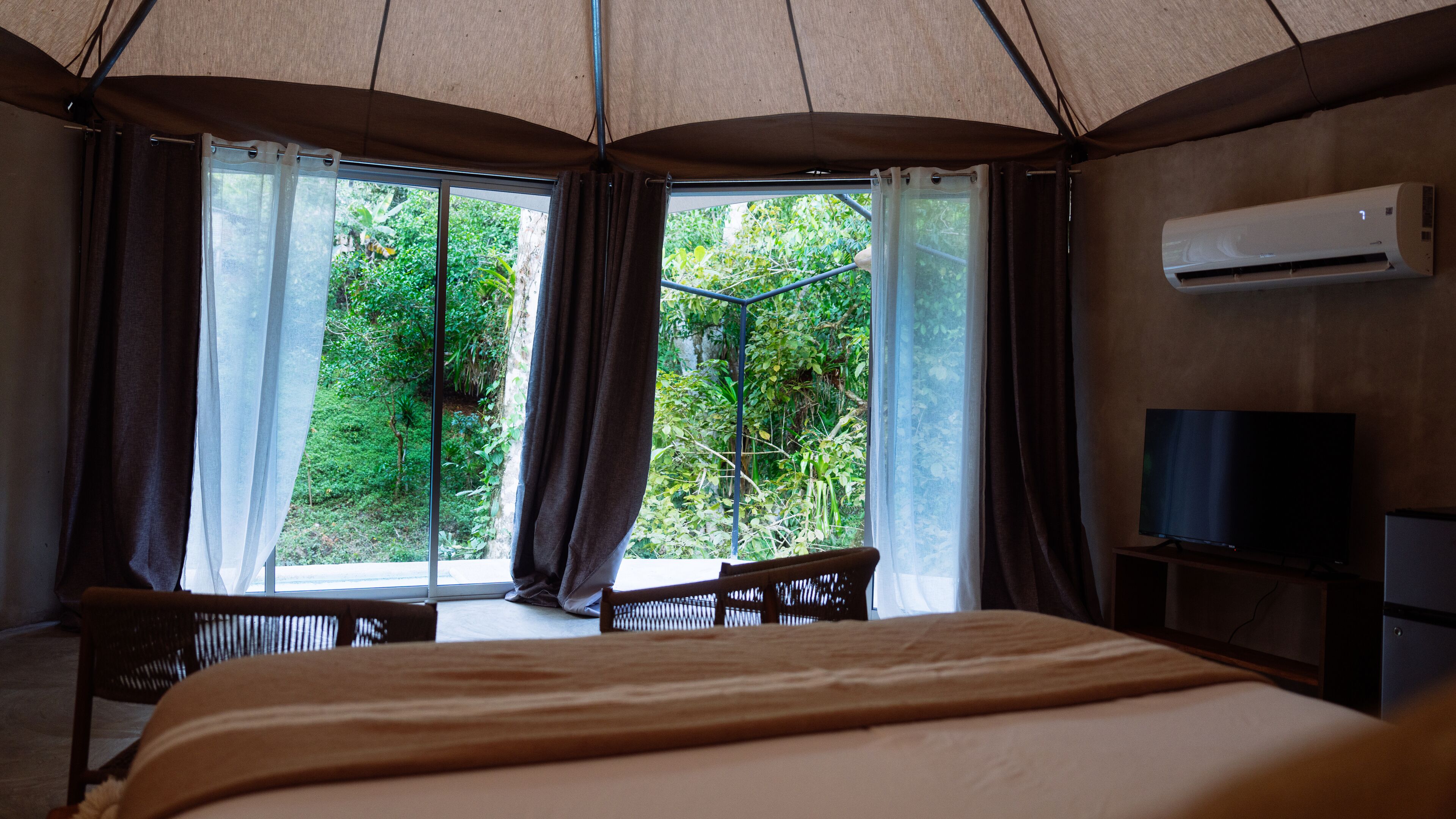 Une chambre avec un lit, une télévision et une fenêtre avec des rideaux.
