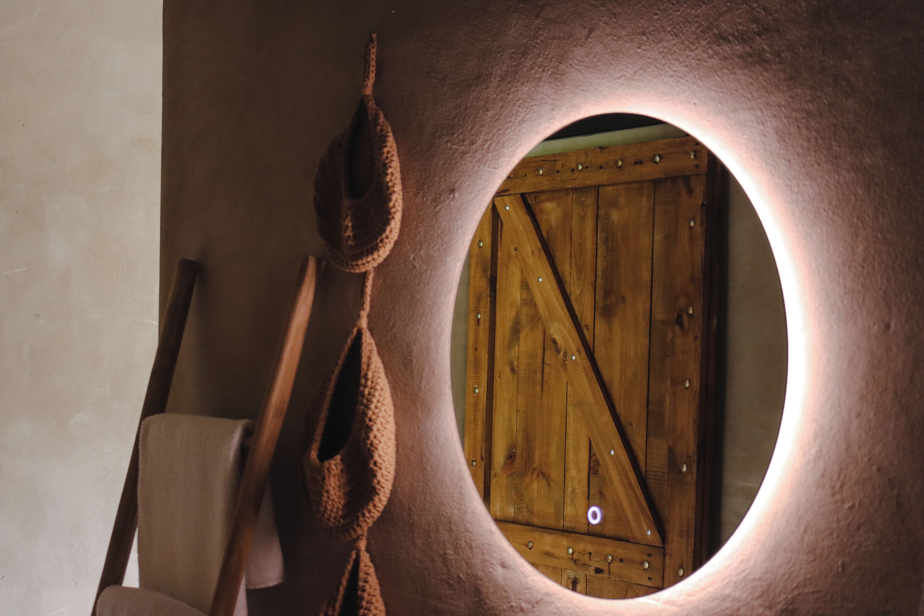 A circular window with a wooden door, a hanging basket, and a chair.
