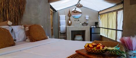 A cozy bedroom with a large bed, a small fireplace, and a breakfast tray on the nightstand.