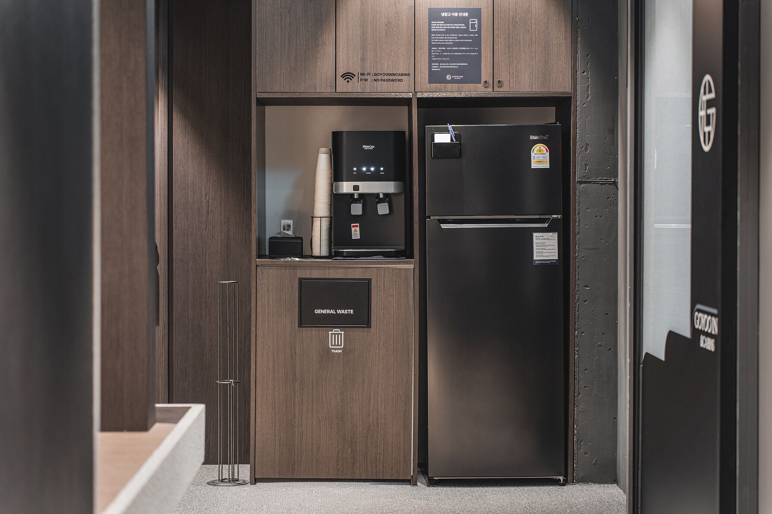 A compact kitchenette with a water dispenser, a coffee machine, and a refrigerator.