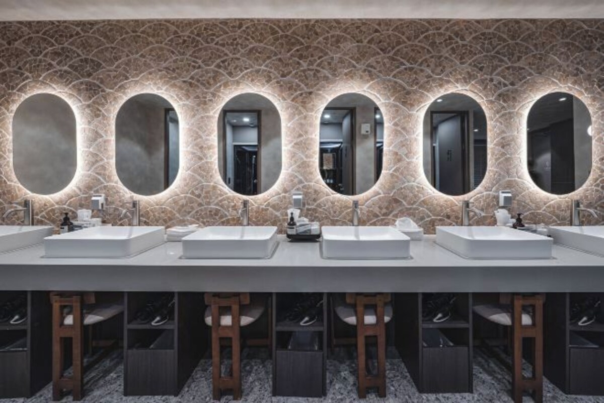 A modern bathroom with three sinks, each with a mirror above.