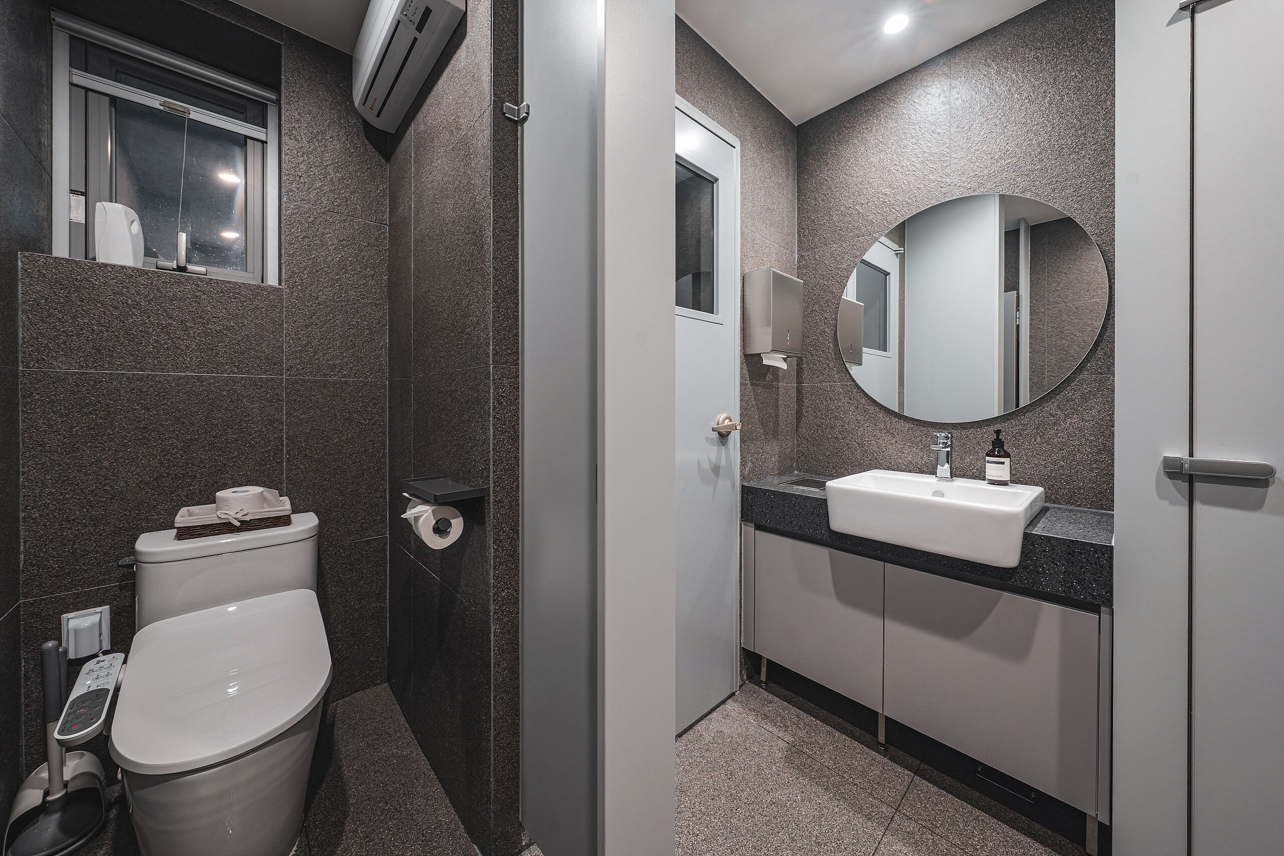 A modern bathroom with a toilet, sink, and mirror.