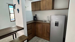 Une cuisine compacte avec des meubles en bois, un réfrigérateur en acier inoxydable, une machine à café et un évier.