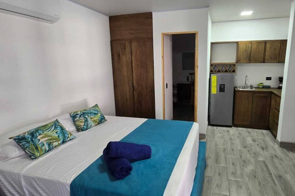 Un dormitorio con cama, una colcha azul y un armario de madera.