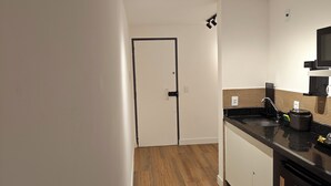 A modern kitchen with wooden flooring, a black countertop, and a built-in dishwasher. - Flat 109 norte novo e completo (Brasilia)