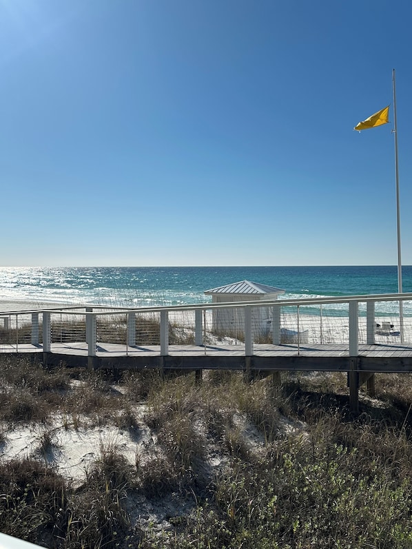 A beach with a wooden boardwalk, a flag, and a small structure.