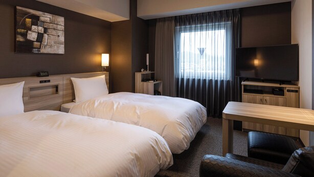 A hotel room with two beds, a desk, a TV, and a window with curtains. - Hotel Route Inn Imizu (Imizu)