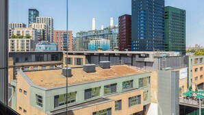 A cityscape with modern buildings, including a prominent high-rise with a unique facade and a building with a flat roof and large windows. - GuestReady - Modern 1BR by Battersea Park (London)