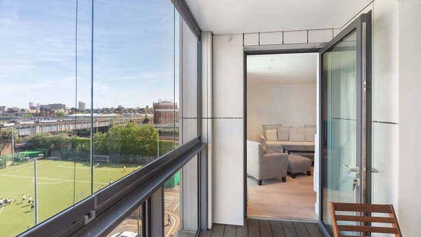 A balcony with a view of a sports field and a cityscape. - GuestReady - Modern 1BR by Battersea Park (London)