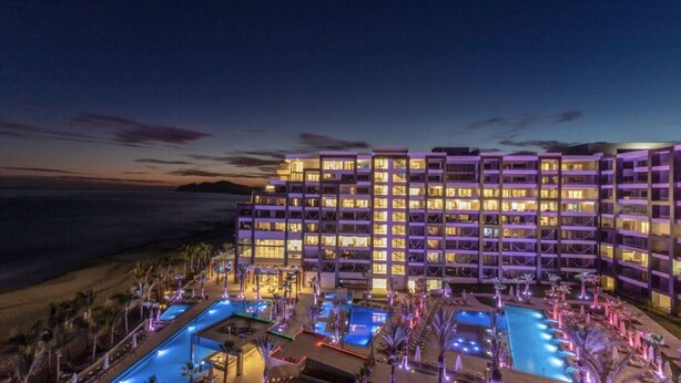 Ett hotell med flera balkonger, ett poolområde och utsikt över havet.