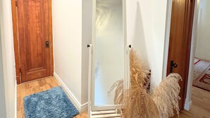 Un pasillo con suelo de madera, un tapete azul, una puerta blanca y una puerta de madera.