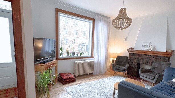 Amplia sala de estar con un ventanal grande, chimenea, televisor y un sofá azul.