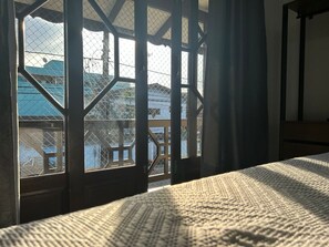 A room with a large window overlooking a balcony with a view of buildings and a blue sky. - Apartamento No Costa e Silva (Joinville)