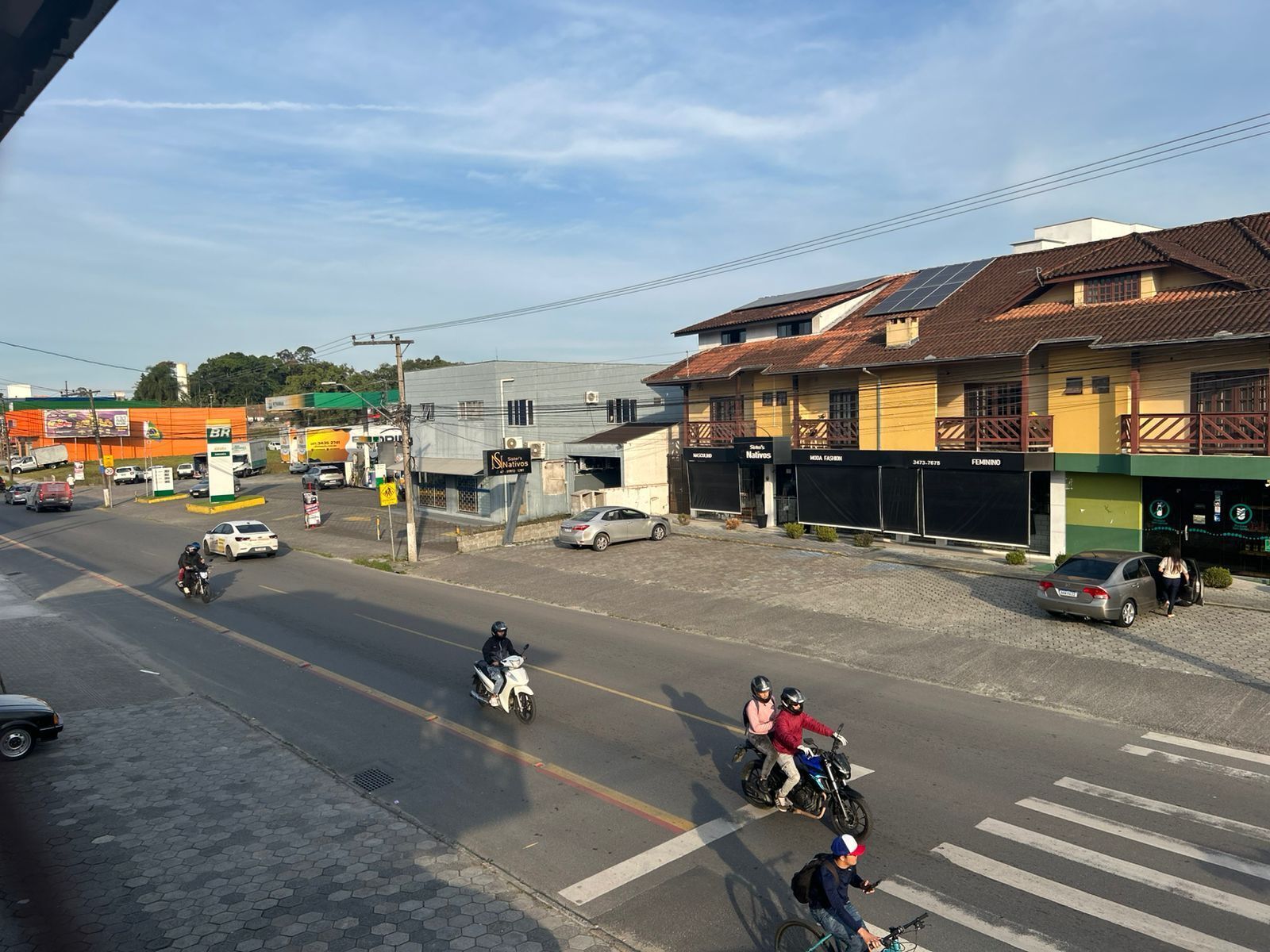 Vista de la calle con edificios, una gasolinera y vehículos.