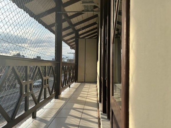 A corridor with a metal railing and a glass door, leading to a room with a view of the sky. - Apartamento No Costa e Silva (Joinville)