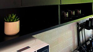 A kitchen with black cabinets, a small potted plant, and a coffee machine.