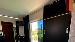 A modern bedroom with a large bed, a wardrobe, and a sliding glass door leading to a balcony.
